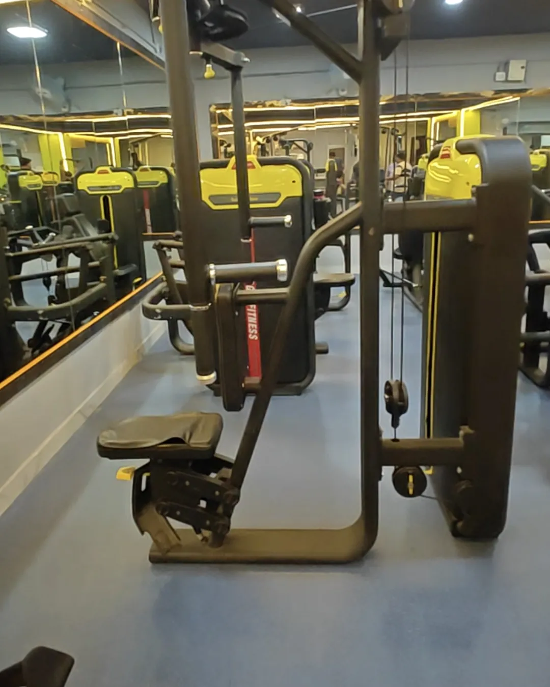 New black and yellow strength machines along the mirror wall at Gym-18